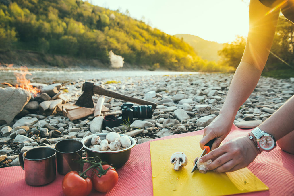 Healthy Eating While Camping - Chopping Veggies by a Rocky River
